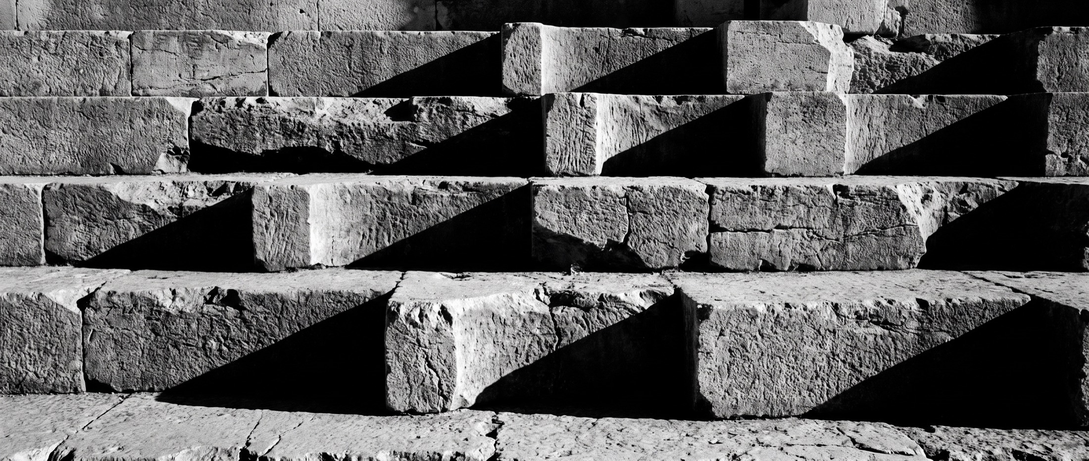 Raking light across the cut treads of an ancient stone staircase